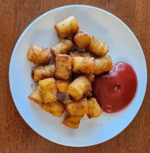homemade fresh tater tots on white plate with ketchup